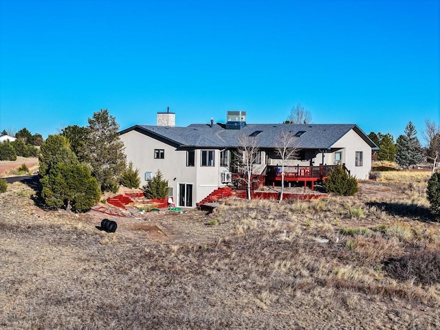 back of house with central air condition unit, a chimney, a deck, and stucco siding