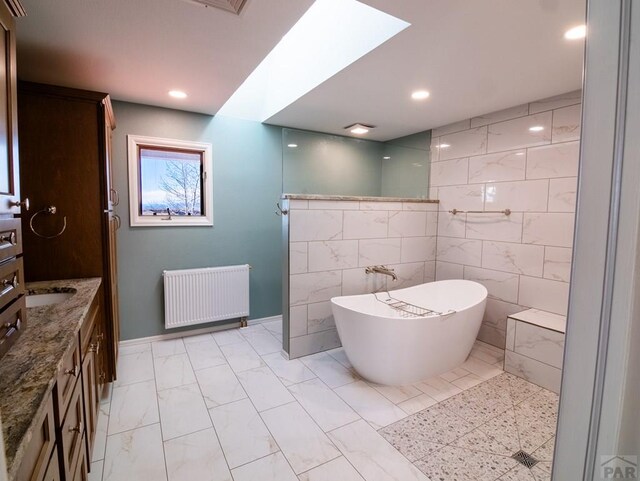 full bath featuring marble finish floor, recessed lighting, a freestanding bath, radiator heating unit, and vanity