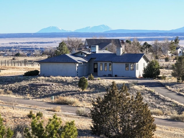 view of front facade featuring a mountain view, a chimney, and fence