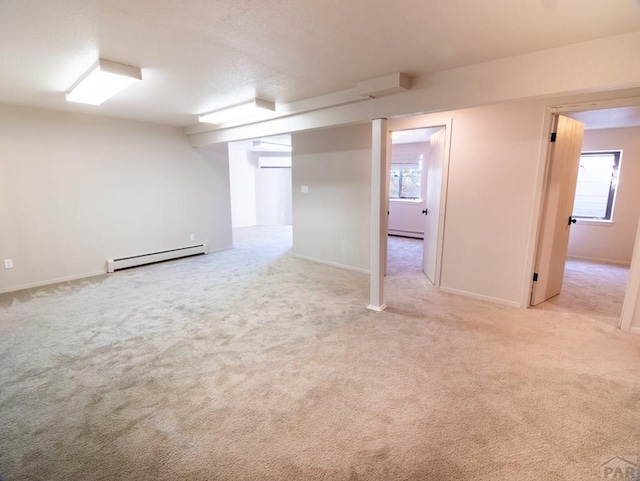 basement with light carpet, a baseboard radiator, a baseboard heating unit, and a wall mounted AC