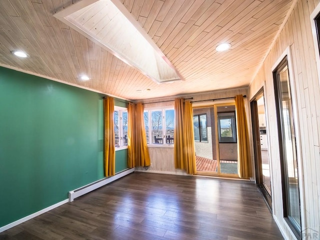 empty room featuring a baseboard heating unit, a skylight, wood ceiling, baseboards, and dark wood finished floors