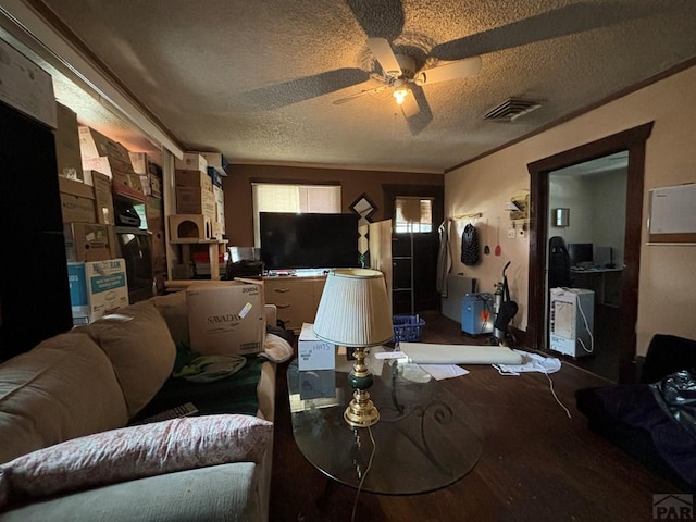 living room with crown molding, visible vents, a ceiling fan, a textured ceiling, and wood finished floors