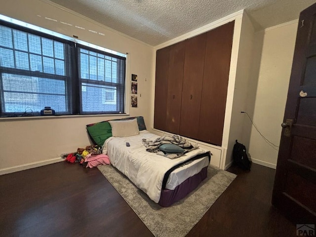 bedroom featuring dark wood-style floors, a closet, multiple windows, and a textured ceiling