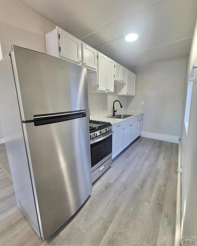 1025 W 17th St, Pueblo, CO 81003 - kitchen with appliances with stainless steel finishes, a sink, white cabinets, light countertops, and light wood-style flooring