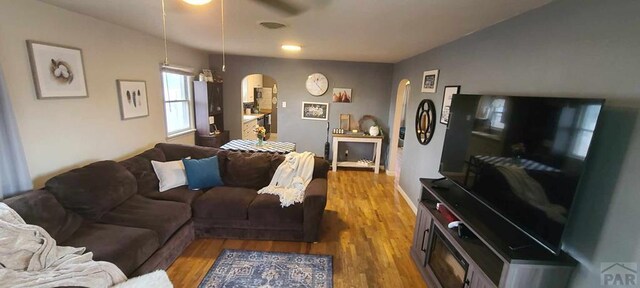 living room with baseboards, visible vents, arched walkways, and wood finished floors