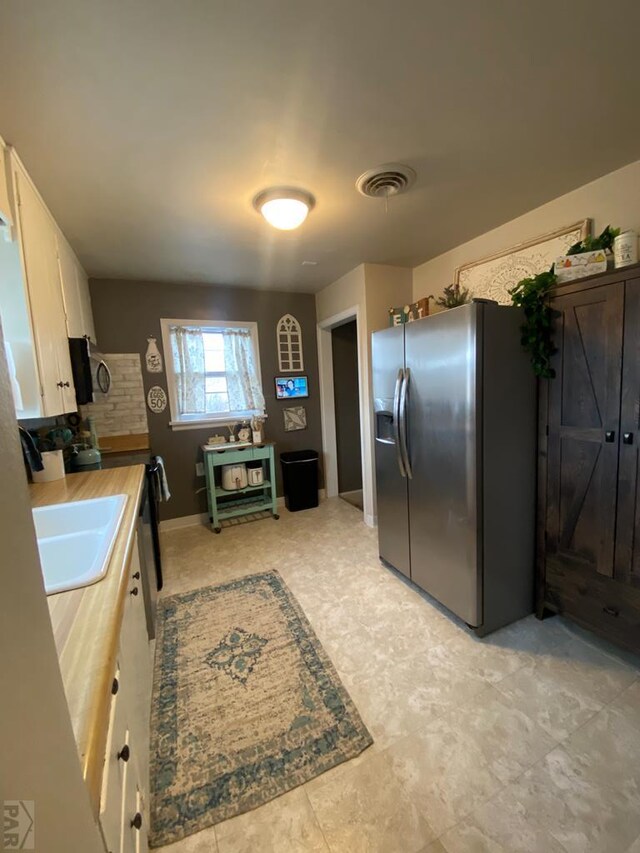 kitchen featuring stainless steel appliances, a sink, visible vents, white cabinets, and light countertops