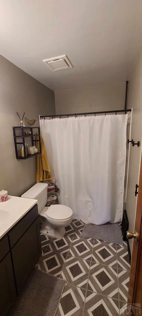 bathroom with curtained shower, visible vents, vanity, and toilet