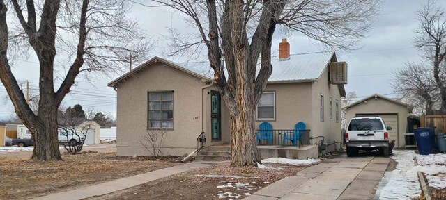 view of front of house with an outbuilding, a chimney, metal roof, and stucco siding