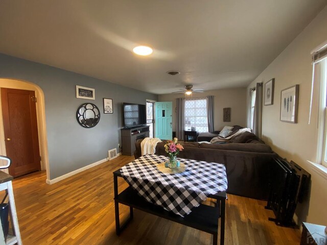 dining space featuring arched walkways, visible vents, baseboards, and wood finished floors