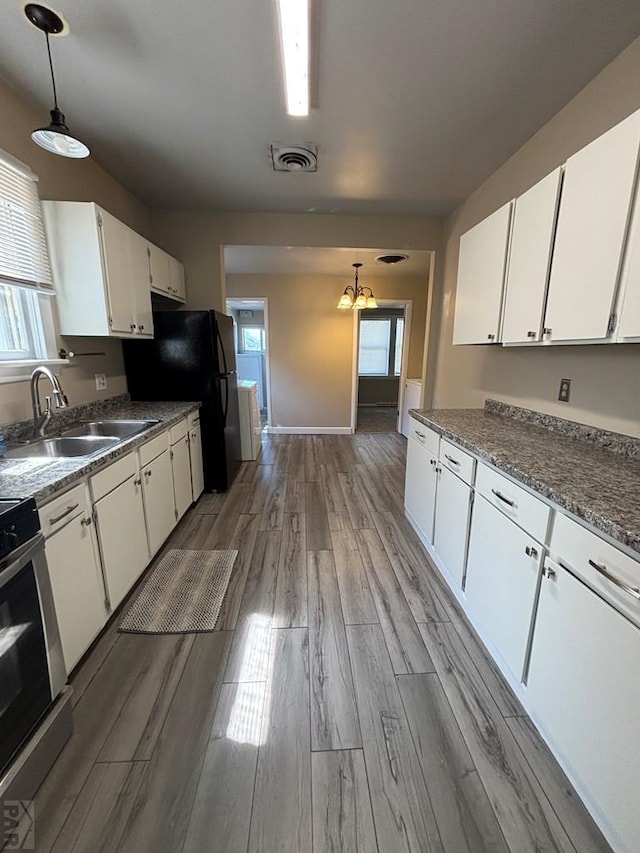 1610 E 6th St, Pueblo, CO 81001 - kitchen featuring a sink, stainless steel stove, light wood-style floors, white cabinets, and a chandelier