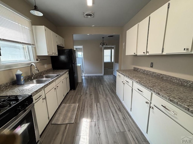 1610 E 6th St, Pueblo, CO 81001 - kitchen featuring a sink, white cabinetry, freestanding refrigerator, light wood-style flooring, and pendant lighting
