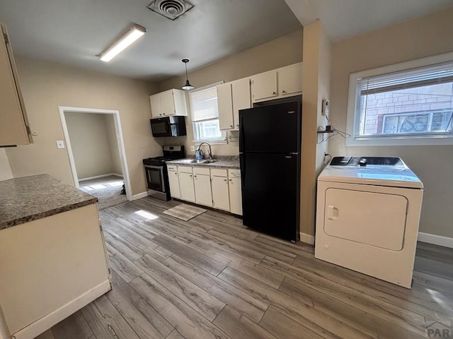 1610 E 6th St, Pueblo, CO 81001 - kitchen with black appliances, washer / dryer, and light wood-style floors