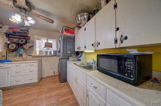 2101 Salt Dr, Colorado Springs, CO 80910 - kitchen with stacked washing machine and dryer, black microwave, a sink, and white cabinets