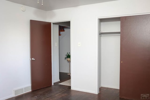 unfurnished bedroom featuring a closet, wood finished floors, visible vents, and baseboards