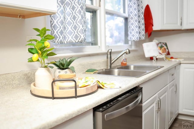 kitchen with light countertops, stainless steel dishwasher, a sink, and white cabinets