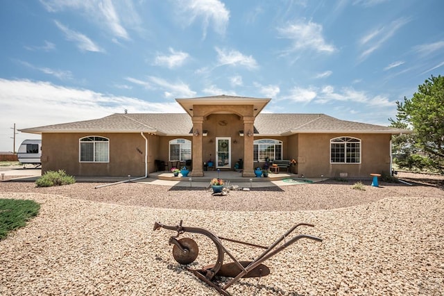 back of property with a patio and stucco siding