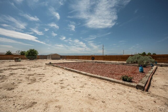 view of yard with a fenced backyard, a storage unit, an outdoor structure, and a rural view