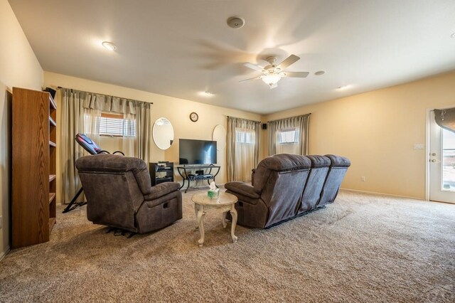 living room with a ceiling fan, a wealth of natural light, and light colored carpet