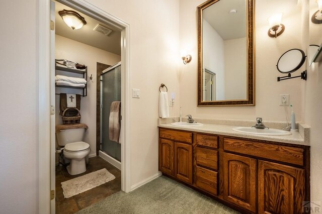 bathroom with visible vents, a sink, a shower stall, and double vanity