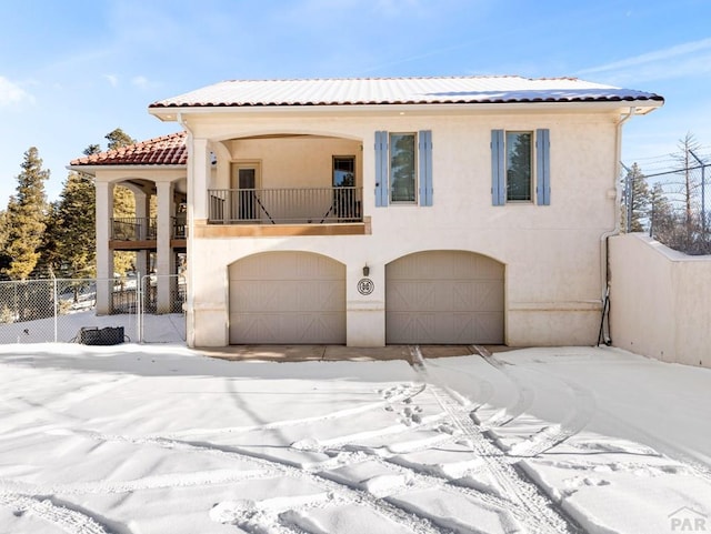 mediterranean / spanish-style house with a tiled roof, fence, a balcony, and stucco siding