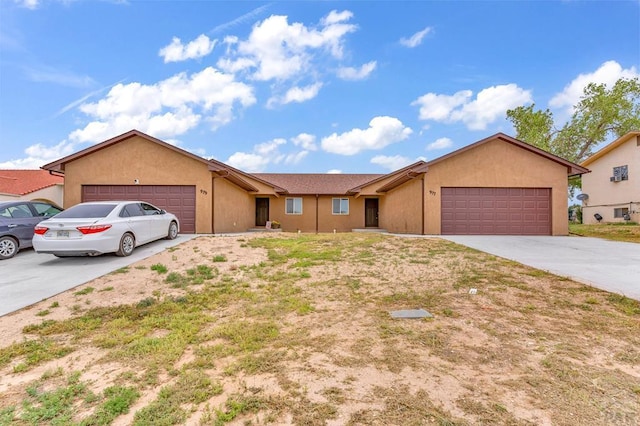 ranch-style house featuring driveway, an attached garage, and stucco siding