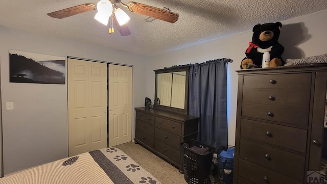 bedroom featuring a textured ceiling, ceiling fan, a closet, and light colored carpet