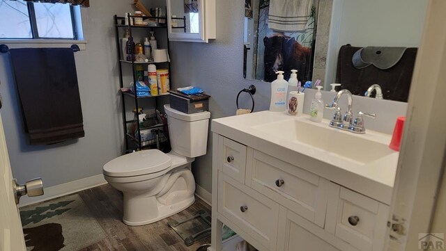 bathroom with vanity, wood finished floors, toilet, and baseboards