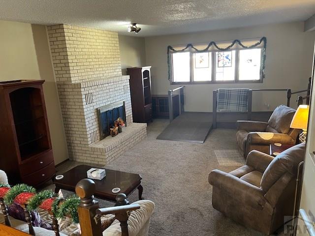 living room with a fireplace, a textured ceiling, and carpet flooring