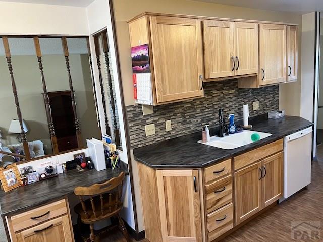 kitchen featuring dishwasher, a sink, dark countertops, and built in study area