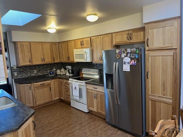 kitchen featuring white appliances, dark countertops, and backsplash