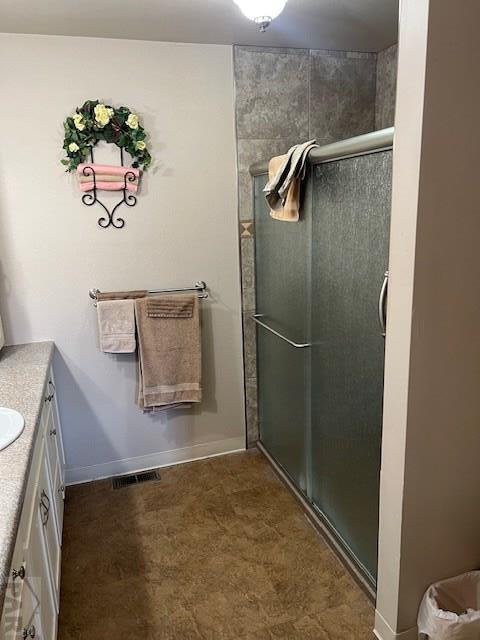 full bath with a shower with door, baseboards, visible vents, and vanity