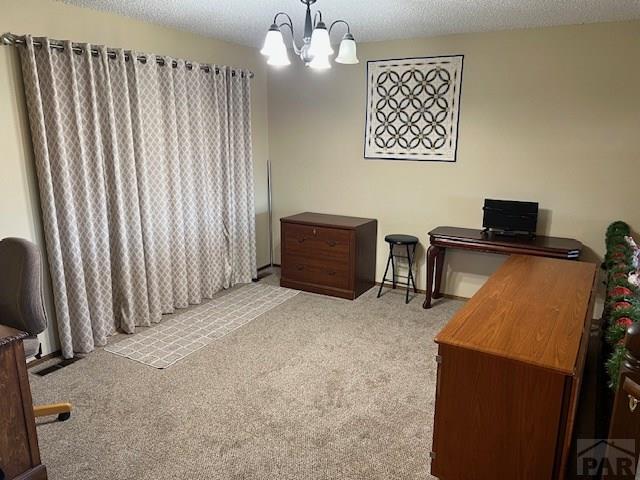 office featuring an inviting chandelier, a textured ceiling, and light colored carpet