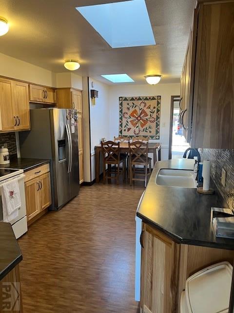 kitchen featuring dark wood-style floors, electric stove, tasteful backsplash, dark countertops, and a sink