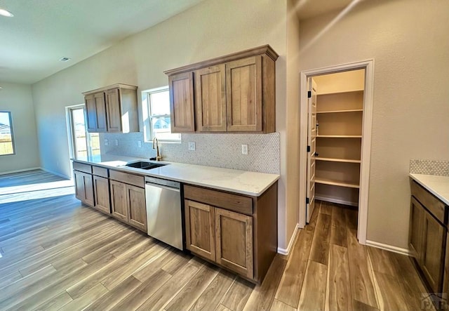 kitchen with dishwasher, backsplash, a sink, and wood finished floors