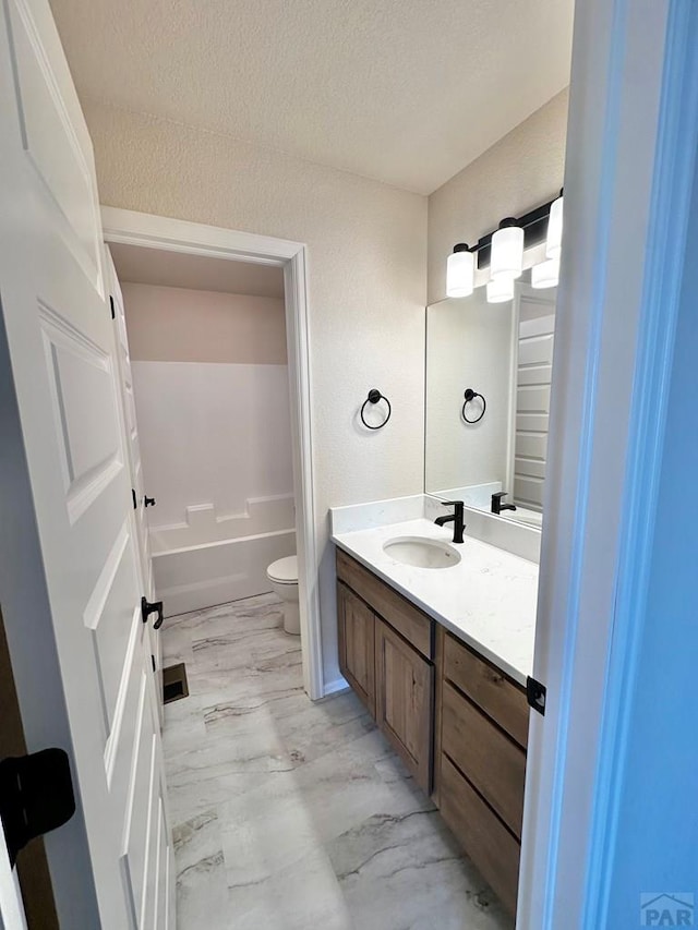 full bathroom featuring toilet, shower / tub combination, marble finish floor, a textured ceiling, and vanity