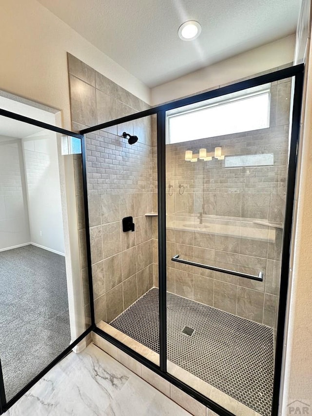 full bathroom with a stall shower, marble finish floor, and a textured ceiling