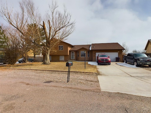 split level home with an attached garage, concrete driveway, and stucco siding