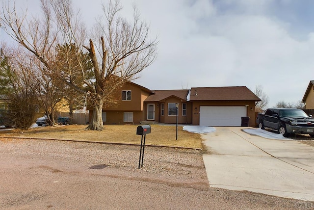 tri-level home featuring concrete driveway, an attached garage, and stucco siding