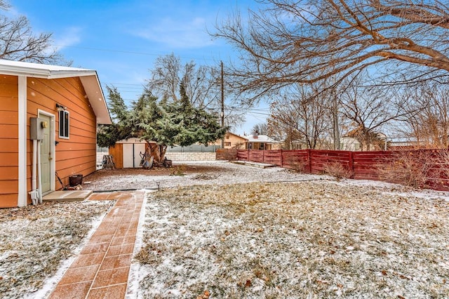 snowy yard with an outbuilding, a shed, and a fenced backyard