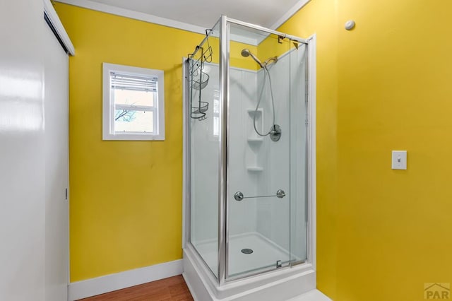 full bathroom featuring a shower stall, crown molding, baseboards, and wood finished floors