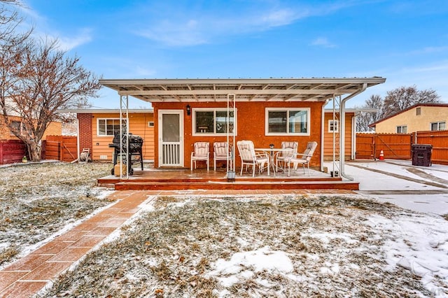 snow covered back of property with a fenced backyard and a deck