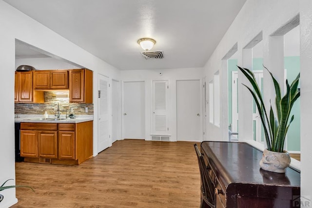 kitchen featuring brown cabinets, light countertops, visible vents, light wood-style floors, and a sink