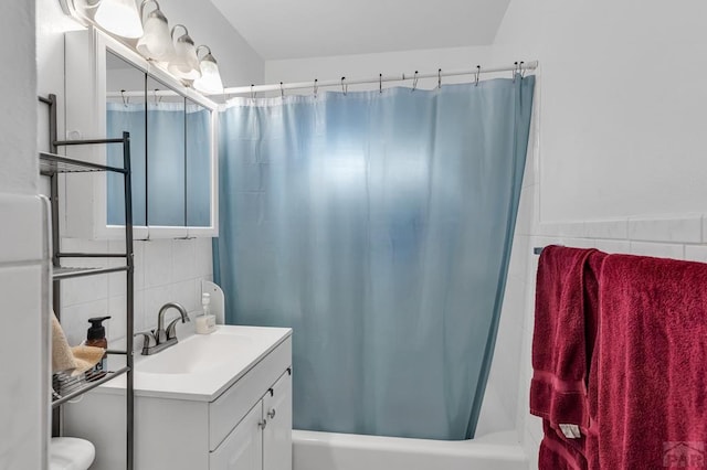 full bath featuring tile walls, vanity, and shower / bath combo