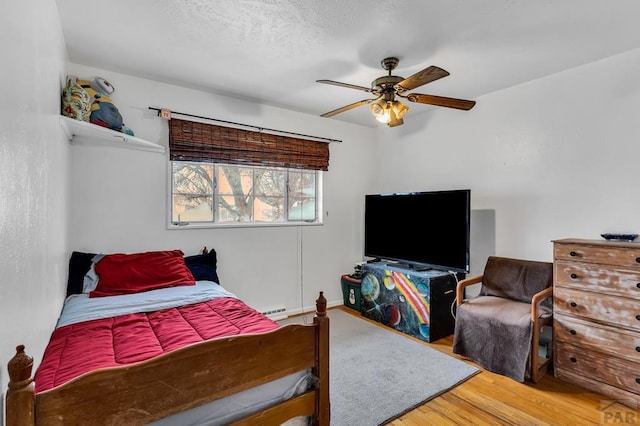 bedroom with a textured ceiling, a ceiling fan, and wood finished floors