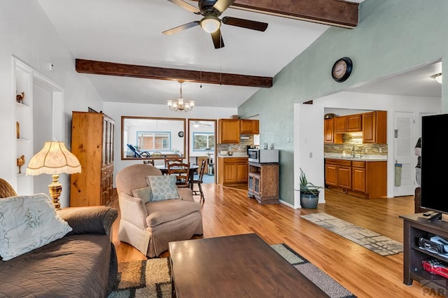 living room featuring light wood-style floors, vaulted ceiling with beams, and ceiling fan with notable chandelier