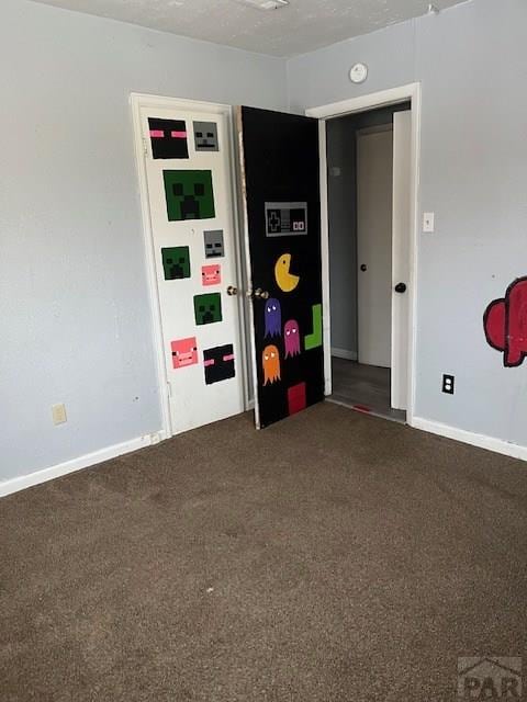 empty room with baseboards, dark colored carpet, and a textured ceiling