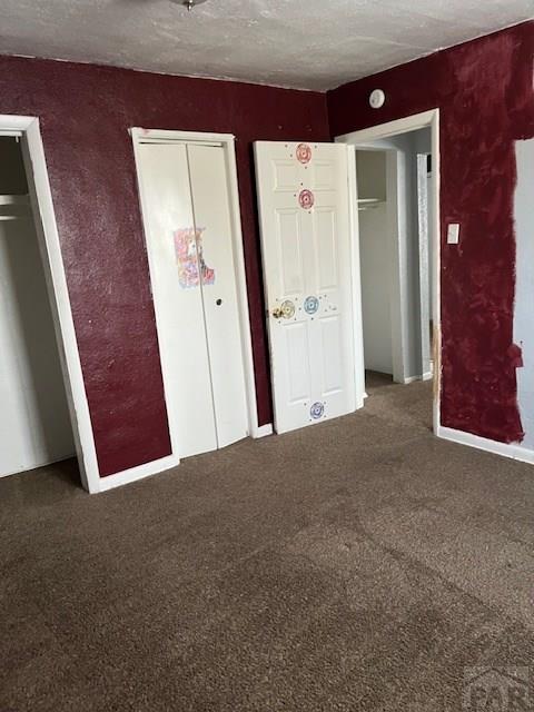 unfurnished bedroom with carpet, multiple closets, and a textured ceiling