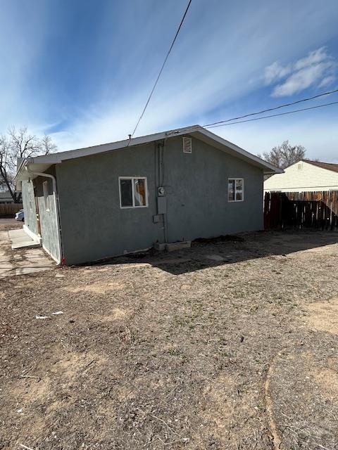 rear view of house with stucco siding and fence