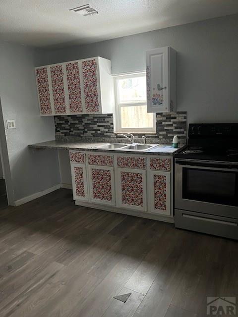 kitchen with visible vents, dark wood finished floors, a sink, decorative backsplash, and range with electric stovetop