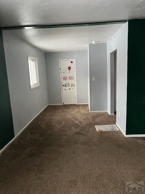 carpeted empty room with a textured ceiling and baseboards